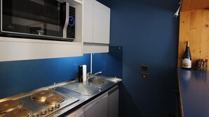 Een kleine keuken met een roestvrijstalen fornuis, een magnetron en een spoelbak.