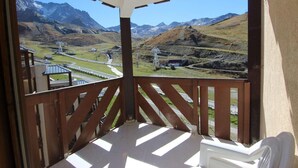 Een balkon met uitzicht op een bergachtig landschap, inclusief een weg en elektriciteitskabels.