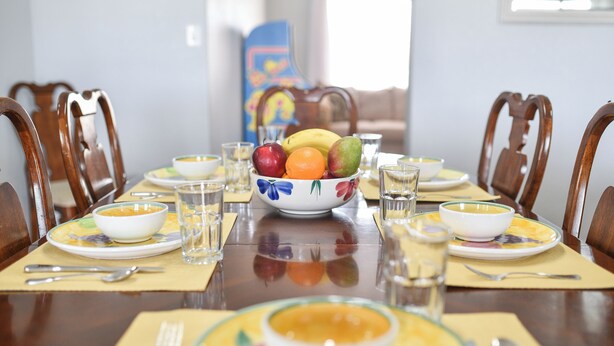A dining table set with bowls of soup, plates, and a bowl of fruit. - TMK-Spacious 4br home with pool for your comfort. EV charger available (Yuma)