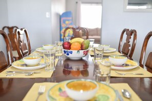 A dining table set with bowls of soup, plates, and a bowl of fruit.