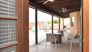 An open doorway leading to a covered patio area with a ceiling fan, outdoor seating, and a view of a swimming pool. - TMK-Spacious 4br home with pool for your comfort. EV charger available (Yuma)