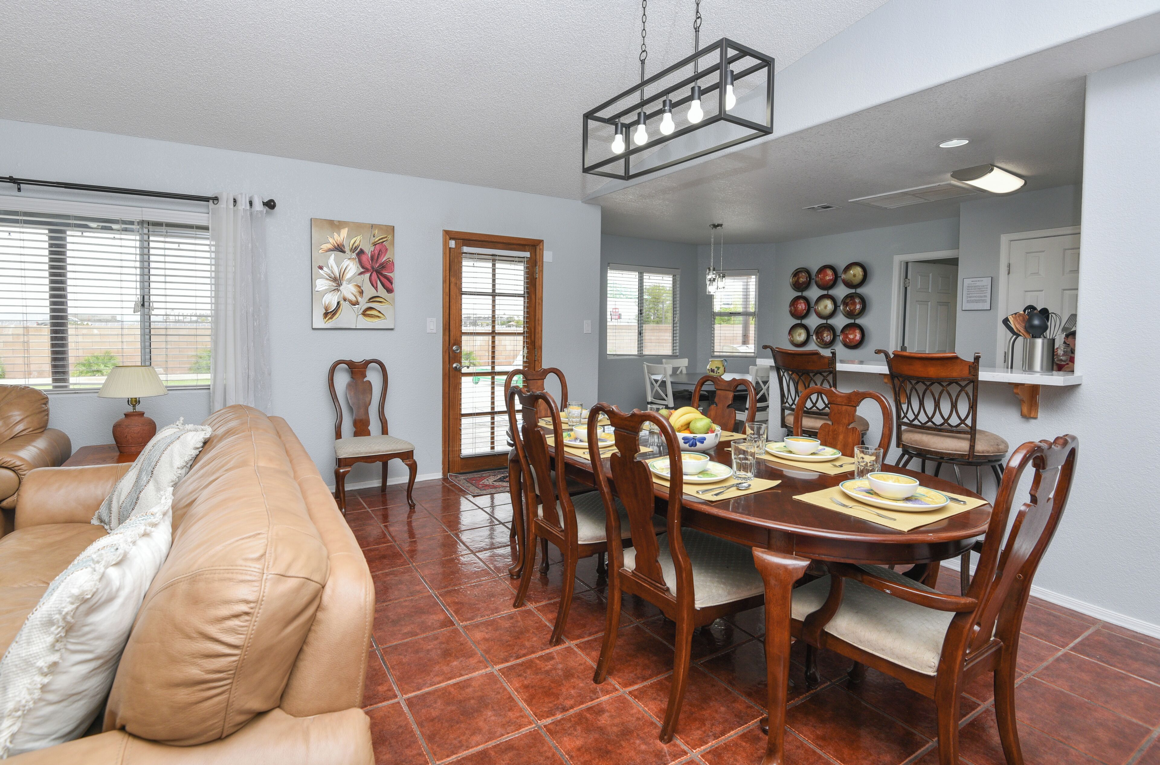 A dining area with a round table, wooden chairs, and a chandelier.