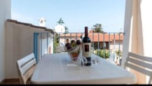 Een balkon met een tafel gedekt voor twee personen, een fles wijn en een glas water.