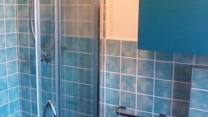 Een badkamer met blauw betegelde wanden en een douchecabine.