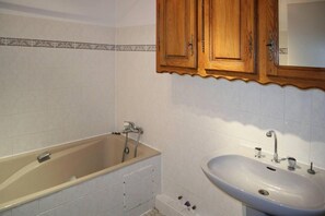 A bathroom with a bathtub, a sink, and wooden cabinets.