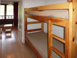 A bunk bed with a wooden frame and a mattress. - Ski-in/ski-out & foot of the slopes, 5th floor, balcony, tv, 22m², Les Orres (Les Orres)
