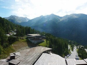 A mountain lodge with a view of surrounding peaks, a paved area with a building, and a road with parked cars. - Ski-in/ski-out & foot of the slopes, 5th floor, balcony, tv, 30m², Les Orres (Les Orres)