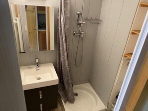 A small bathroom with a sink, mirror, shower, and a wooden cabinet. - Ski-in/ski-out & foot of the slopes, 1st floor, view ski slopes, terrace, tv, ski locker, 13m² (Valmorel)