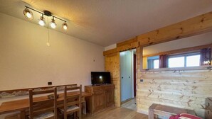 A cozy room with a wooden dining table, chairs, a television, and a bed. - 200m from ski slopes, 1st floor, view ski slopes, balcony, tv, ski locker, 26m², Valmorel (Valmorel)