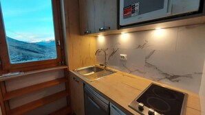 A compact kitchen with a built-in stove, a sink, and a microwave. - 200m from ski slopes, 1st floor, view ski slopes, balcony, tv, ski locker, 26m², Valmorel (Valmorel)