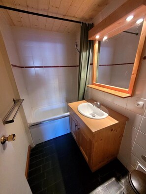 Ein kleines Badezimmer mit einer Badewanne, einem Waschbecken und einem Spiegel.
