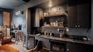 A modern kitchen with dark cabinetry, a black countertop, and a decorative shelf with glassware and a bird sculpture.