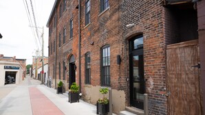 A brick building with large windows and a red brick sidewalk.