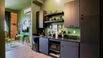 Una cocina moderna con armarios oscuros, microondas integrado y una pared decorada con ladrillo.