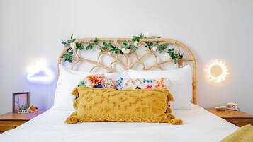 A bed with a white headboard, a yellow throw blanket, and a colorful pillow.
