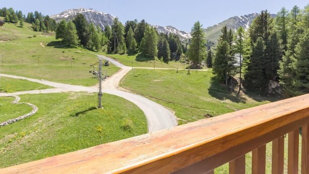 A mountainous landscape with a winding road and a wooden railing.