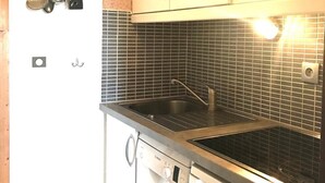 Keittiössä on valkoiset kaapit, ruostumattomasta teräksestä valmistettu pesuallas ja Bosch-astianpesukone.