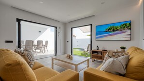 A modern living room with a sofa, coffee table, and a large TV screen displaying a beach scene. - PRIVATE HEATED POOL - Fully refurbished in 2022 (San Bartolomé de Tirajana)