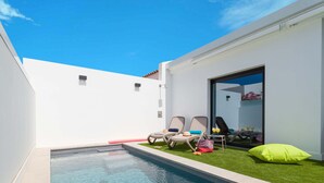 A modern outdoor pool area with clear blue water, surrounded by white walls and a small grassy patch. - PRIVATE HEATED POOL - Fully refurbished in 2022 (San Bartolomé de Tirajana)