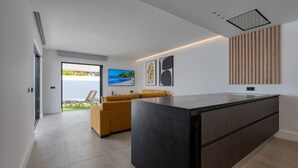 A modern kitchen with a large island, a yellow sofa, and a view of a beach through the sliding glass door. - PRIVATE HEATED POOL - Fully refurbished in 2022 (San Bartolomé de Tirajana)