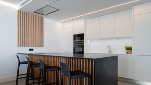 A modern kitchen with a central island, bar stools, white cabinetry, and a wooden accent wall. - PRIVATE HEATED POOL - Fully refurbished in 2022 (San Bartolomé de Tirajana)