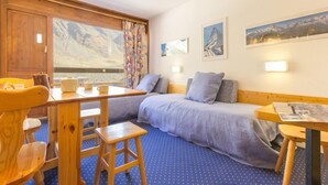 Una stanza accogliente con un letto, un tavolo di legno e una finestra vista montagna.