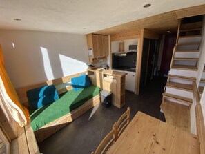 Ein kompakter, offener Raum mit Bett, Küchenzeile und Essbereich.