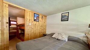 Una habitación con una litera, un armario de madera y dos cuadros en la pared.