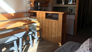 Una cocina compacta con armarios de madera, microondas, cafetera y refrigerador.