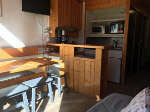 Kompakti keittiö, jossa on puukaapit, mikroaaltouuni, kahvinkeitin ja jääkaappi.