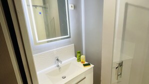 A bathroom with a white sink, a mirror, and a glass shower enclosure.