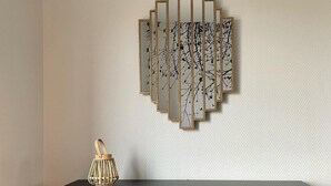 A room with a black console table, a decorative wall piece, and a brown chair.
