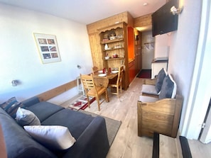 A cozy living room with a sofa, a wooden dining table, and a TV mounted on the wall. - 50m from resort center, 2nd floor, view mountain, tv, 24m², Les Arcs (Les Arcs)