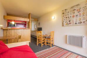 A compact room with a kitchenette, a dining area, and a wall-mounted radiator.