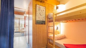 Camera con un letto a castello in legno, un poster appeso al muro, una finestra e una porta che dà su un'altra stanza.