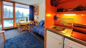 Una stanza compatta con zona pranzo, un letto e angolo cottura.