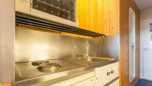 Une cuisine de taille réduite, dotée d’une cuisinière en acier inoxydable, d’un évier et d’armoires en bois.