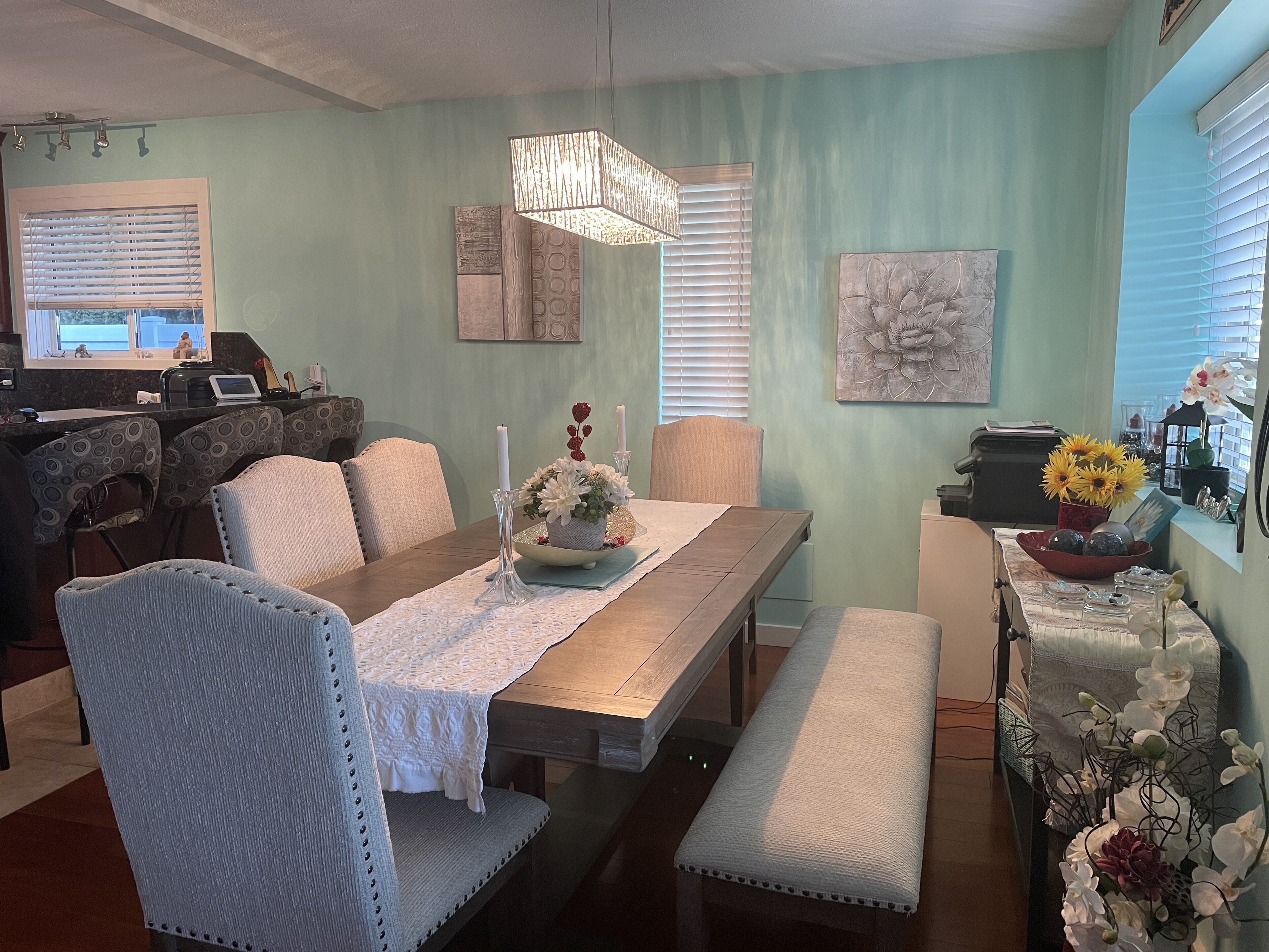 A dining area with a wooden table, cushioned chairs, a bench, and a decorative centerpiece.