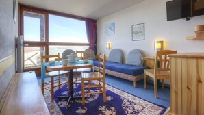 A cozy room with a wooden table, chairs, a sofa, and a TV mounted on the wall. - 10m from resort center, 2nd floor, view valley, balcony, tv, 33m², Les Arcs (Les Arcs)