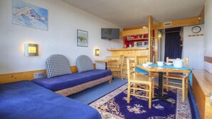 A cozy room with two beds, a dining table with chairs, a kitchen area, and a clock on the wall. - 10m from resort center, 2nd floor, view valley, balcony, tv, 33m², Les Arcs (Les Arcs)