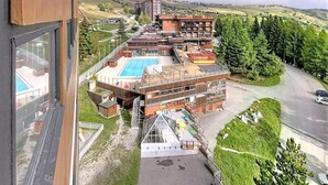 A hotel with a pool, multiple floors, and a view of the surrounding landscape. - 50m from ski slopes, 9th floor, view valley, swimming pool, tv, ski locker, 16m², Le Corbier (Le Corbier)