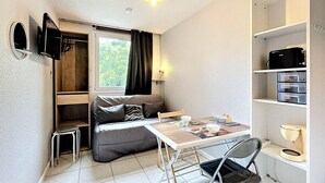 Ein gemütlicher Wohnbereich mit einer Couch, einem Esstisch und einer kleinen Küchenzeile.