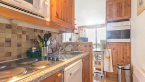 Une cuisine avec des meubles en bois, un plan de travail en granit, un lave-vaisselle, un four à micro-ondes et une cuisinière.