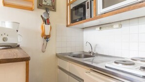 A compact kitchen with a microwave, stove, sink, and a coffee maker on a wooden countertop. - 10m from resort center, 6th floor, view ski slopes, swimming pool, balcony, tv, ski locker, 24m² (Le Corbier)