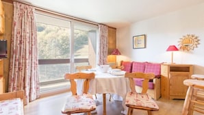 A cozy room with a dining table, chairs, a sofa, and a television. - 50m from ski slopes, 4th floor, view ski slopes, swimming pool, balcony, tv, ski locker, 31m² (Le Corbier)