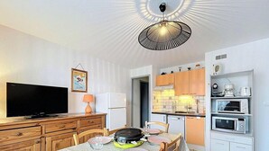 A compact kitchen with a dining area, a television, and a ceiling light fixture.