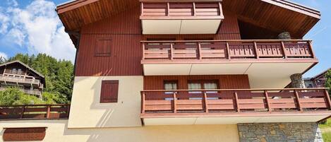 A multi-story chalet with a wooden facade, balconies, and a stone base.