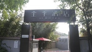The entrance to Ji Hotel with a sign above the gate, a red umbrella, and a notice on the wall. - Ji Hotel (Nanjing)