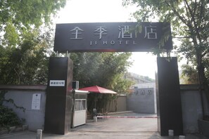 The entrance to Ji Hotel with a sign above the gate, a red umbrella, and a notice on the wall. - Ji Hotel (Nanjing)