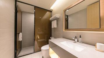 A modern bathroom with a glass shower enclosure, a white toilet, and a vanity with a large mirror.
